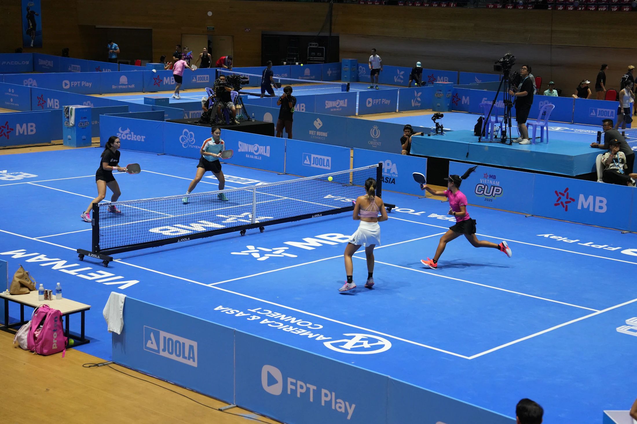 Dos parejas compiten en una pista azul de pickleball